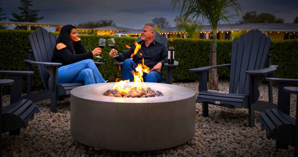 People enjoying wine next to a fire pit with fire.