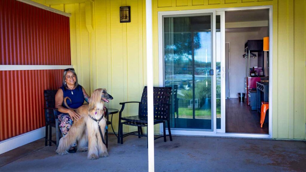 A woman with her dog on a patio with room in background.